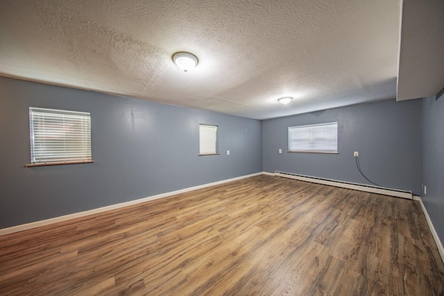 basement featuring hardwood / wood-style floors, a textured ceiling, and a baseboard radiator