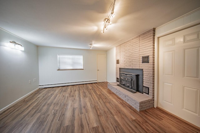 unfurnished living room featuring hardwood / wood-style flooring, a wood stove, ornamental molding, and a baseboard radiator