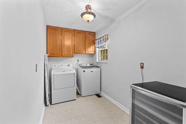 clothes washing area featuring separate washer and dryer, baseboards, and cabinet space