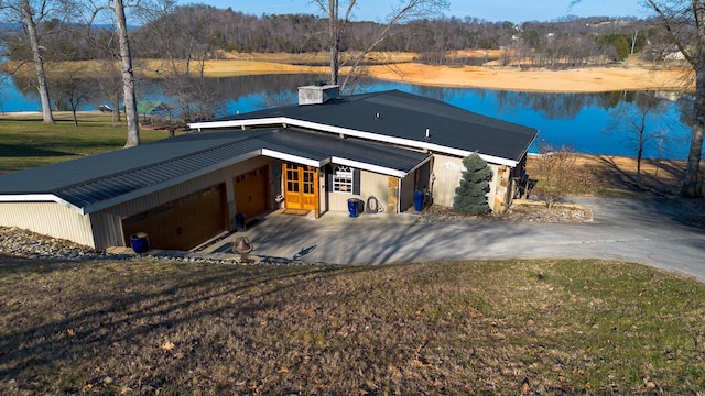 view of front of house with a carport, a water view, a garage, and a front lawn