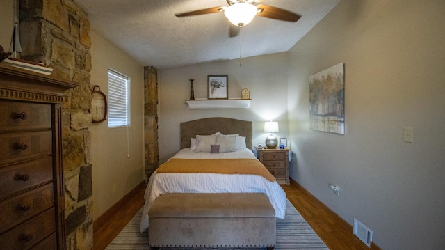 bedroom with a textured ceiling, vaulted ceiling, dark hardwood / wood-style floors, and ceiling fan