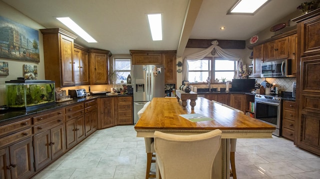 kitchen with butcher block countertops, plenty of natural light, a center island, and appliances with stainless steel finishes