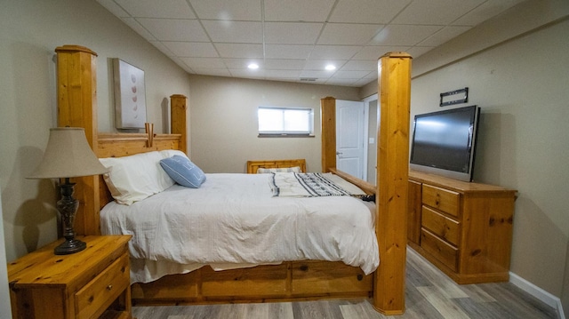 bedroom featuring a drop ceiling and light hardwood / wood-style flooring