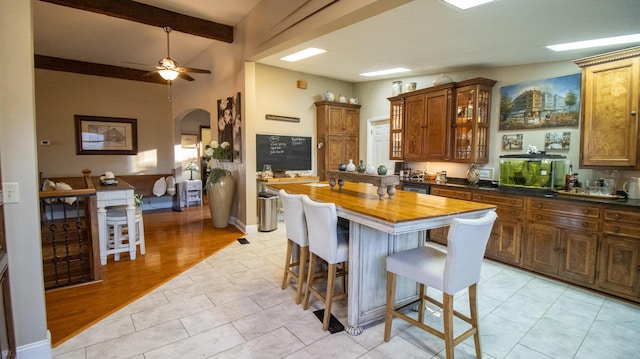 kitchen featuring ceiling fan, a kitchen island, wooden counters, and a kitchen breakfast bar