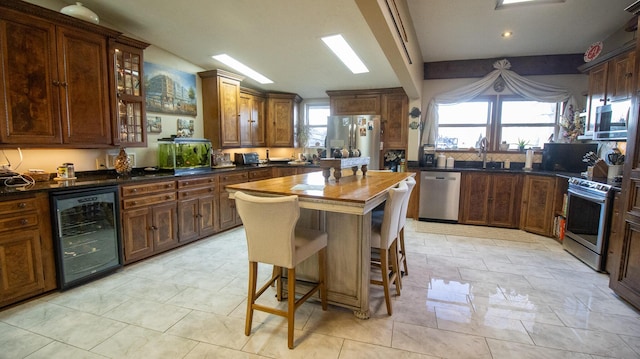 kitchen featuring sink, stainless steel appliances, wine cooler, a kitchen island, and wood counters