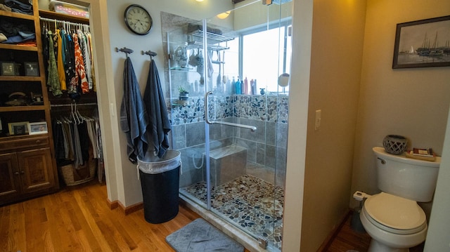 bathroom with wood-type flooring, an enclosed shower, and toilet