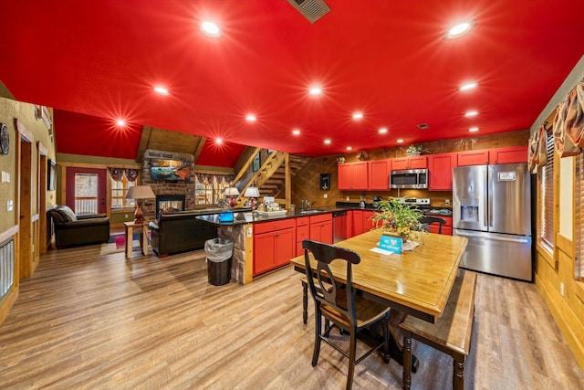 dining space with a stone fireplace, sink, and light wood-type flooring