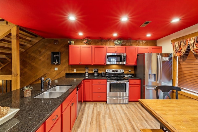 kitchen featuring light wood-type flooring, sink, stainless steel appliances, and dark stone countertops