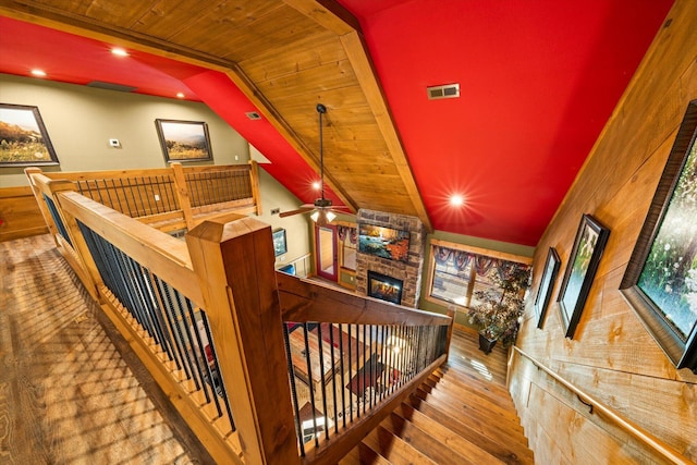 staircase with hardwood / wood-style floors, wooden ceiling, lofted ceiling, ceiling fan, and a fireplace