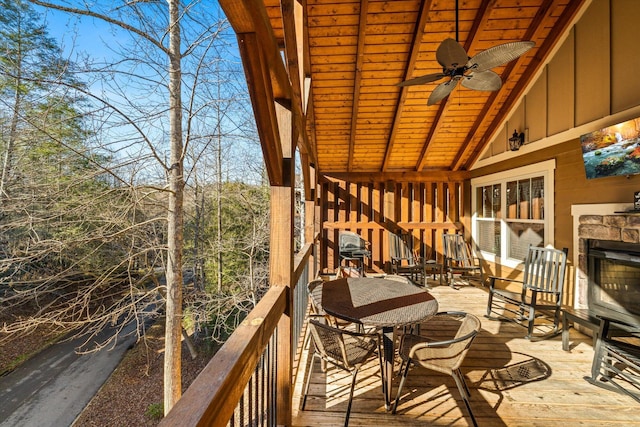 deck with ceiling fan and an outdoor stone fireplace