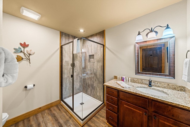 bathroom with toilet, hardwood / wood-style floors, vanity, and walk in shower