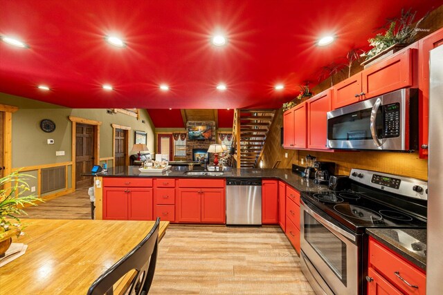 kitchen featuring kitchen peninsula, appliances with stainless steel finishes, sink, light hardwood / wood-style floors, and lofted ceiling