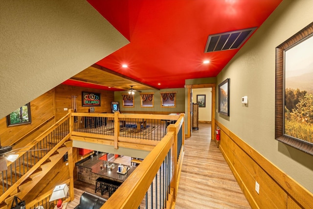 hall featuring light hardwood / wood-style flooring and wood walls