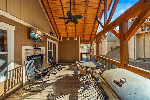 wooden deck with area for grilling, ceiling fan, and exterior fireplace