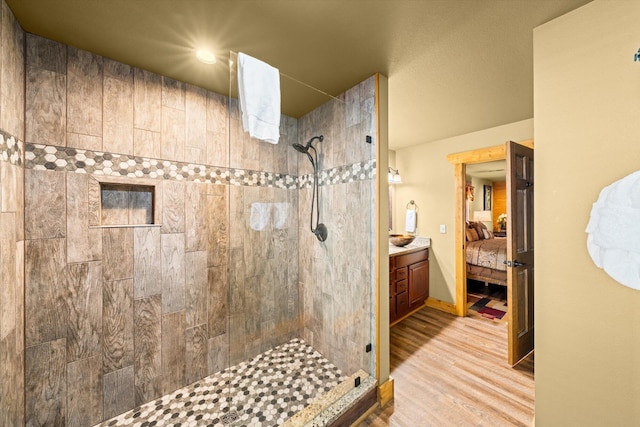 bathroom featuring hardwood / wood-style flooring, vanity, and a tile shower