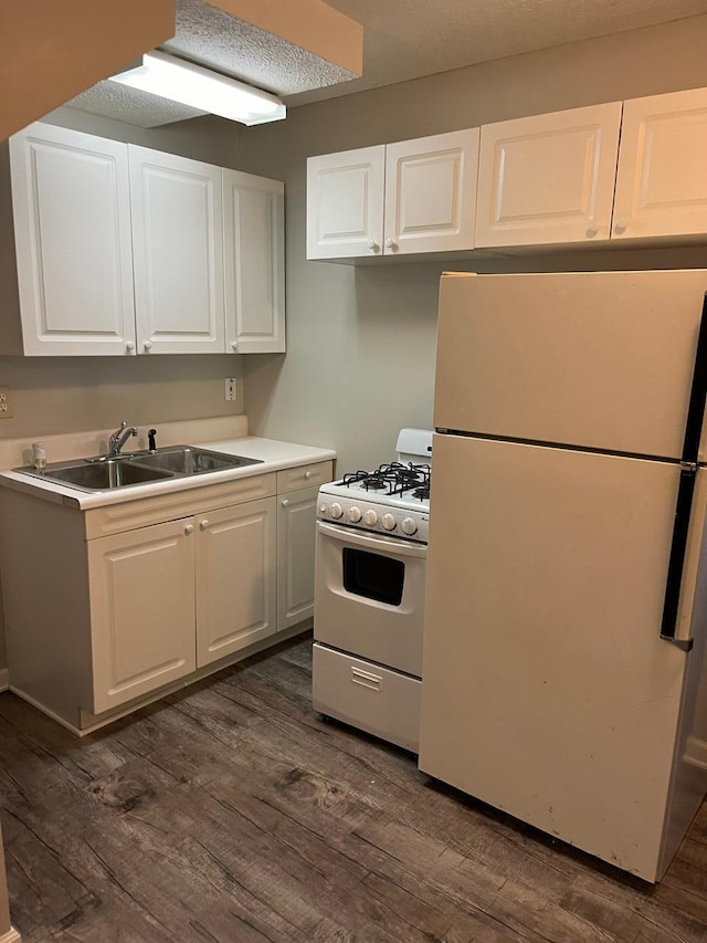 kitchen featuring white cabinetry, sink, white appliances, and dark wood-type flooring