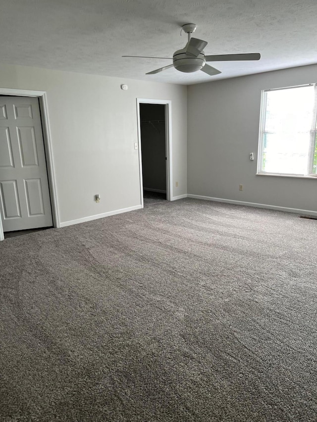 carpeted spare room featuring ceiling fan and a textured ceiling