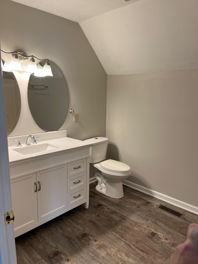 bathroom featuring toilet, lofted ceiling, hardwood / wood-style floors, and vanity