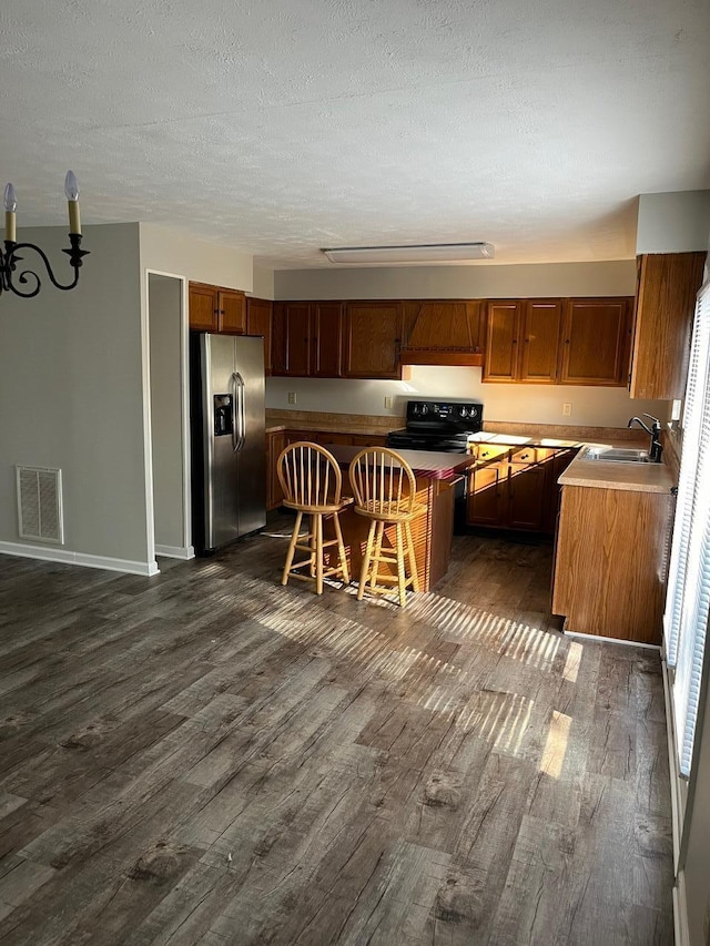 kitchen featuring stainless steel refrigerator with ice dispenser, sink, a kitchen breakfast bar, dark hardwood / wood-style floors, and kitchen peninsula