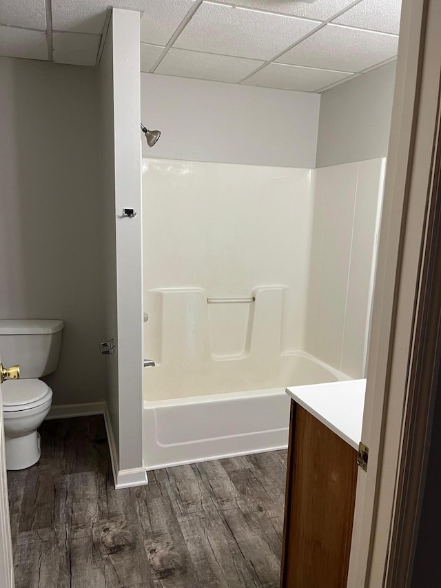 full bathroom featuring toilet, hardwood / wood-style flooring, a paneled ceiling, shower / bathtub combination, and vanity