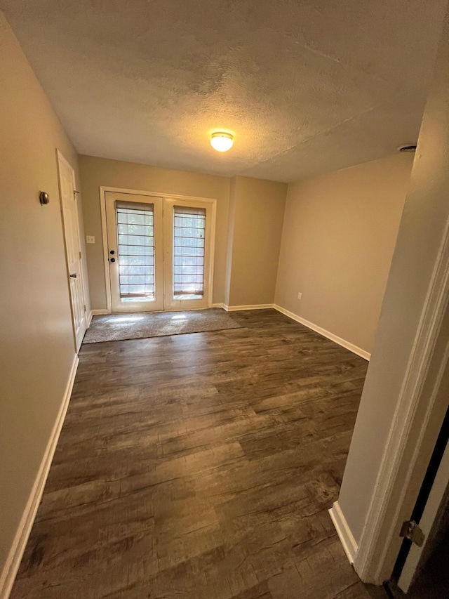 spare room featuring french doors, dark hardwood / wood-style flooring, and a textured ceiling