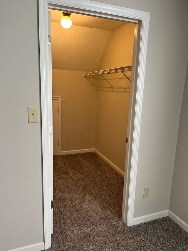 walk in closet featuring lofted ceiling and dark carpet