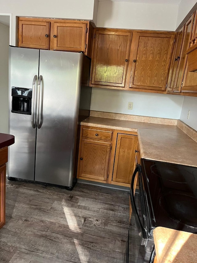 kitchen with stainless steel refrigerator with ice dispenser, dark hardwood / wood-style flooring, and electric stove