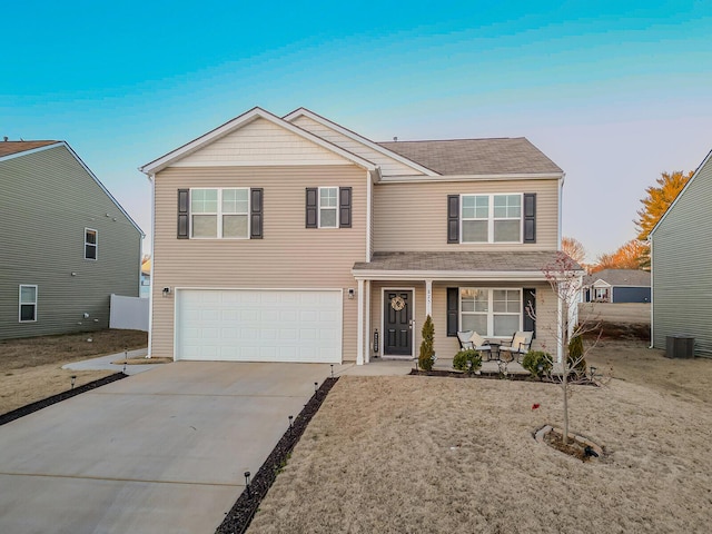 traditional home featuring covered porch, concrete driveway, cooling unit, and a garage