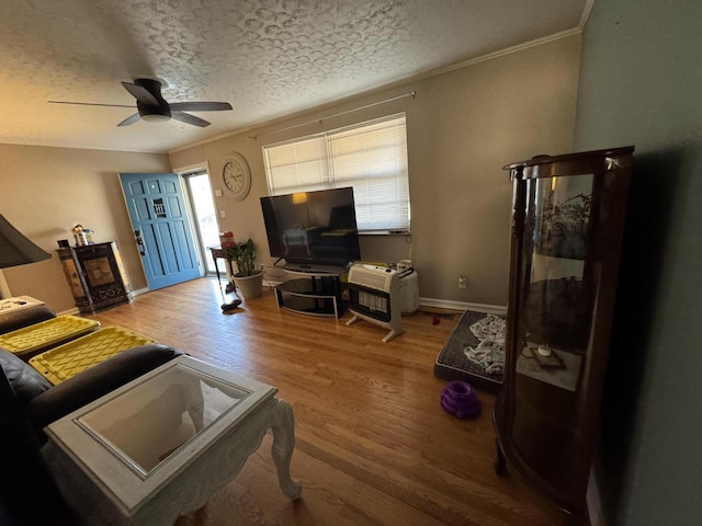 living room featuring crown molding, a textured ceiling, a ceiling fan, and wood finished floors