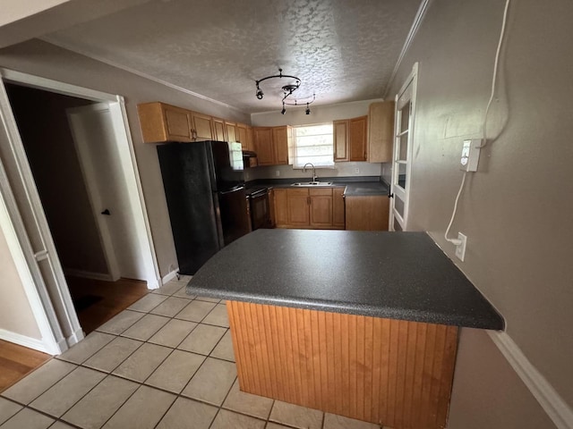 kitchen with dark countertops, baseboards, a sink, light tile patterned floors, and black appliances