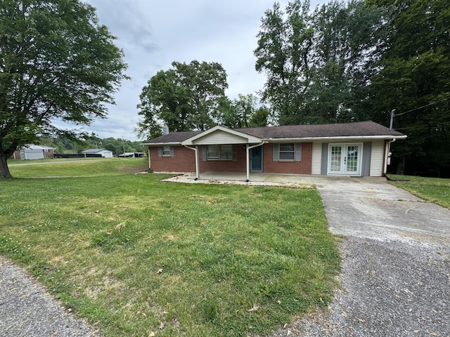 ranch-style home featuring a front lawn, brick siding, a porch, french doors, and driveway