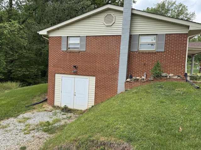 view of property exterior featuring brick siding and a yard