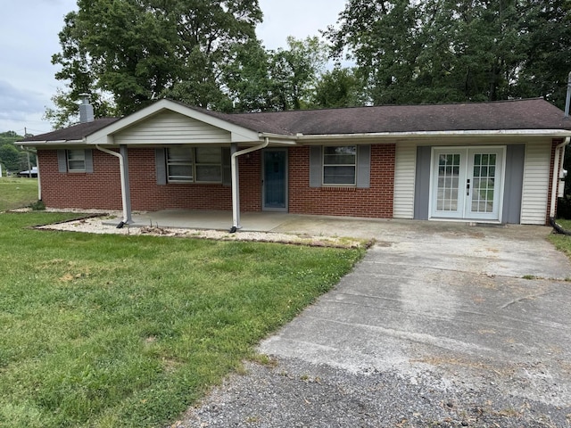 single story home featuring brick siding, french doors, and a front yard