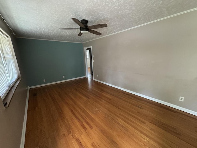 empty room featuring a textured ceiling, a ceiling fan, baseboards, wood finished floors, and ornamental molding