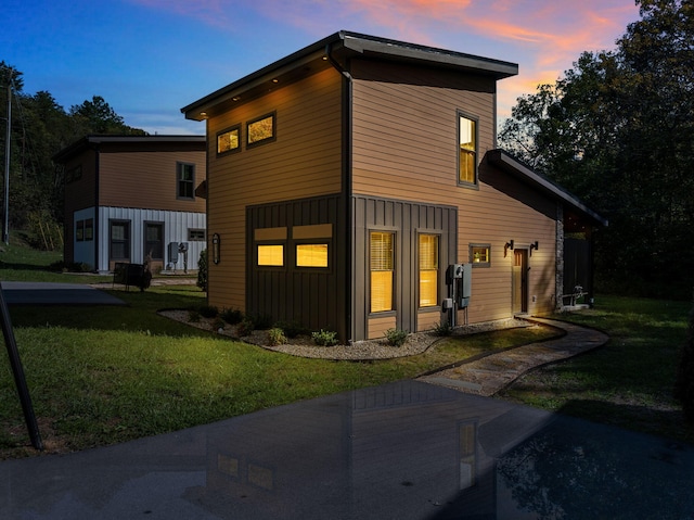 back of property at dusk featuring a yard and board and batten siding