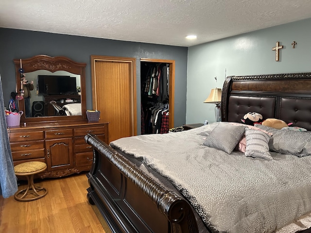 bedroom featuring a textured ceiling, light wood-type flooring, and a closet