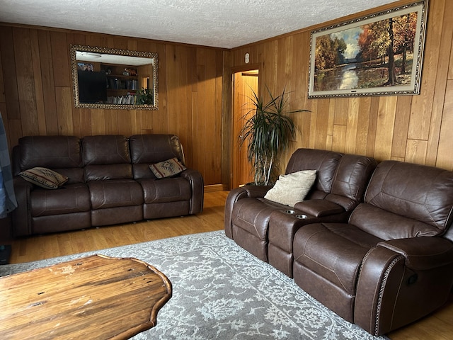 living room featuring wood walls, light hardwood / wood-style floors, and a textured ceiling