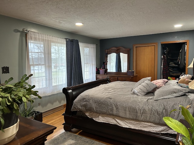 bedroom featuring hardwood / wood-style floors, a textured ceiling, and a baseboard radiator