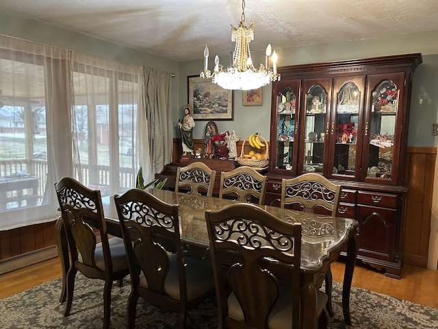 dining area featuring a notable chandelier, a baseboard heating unit, a textured ceiling, and light hardwood / wood-style flooring