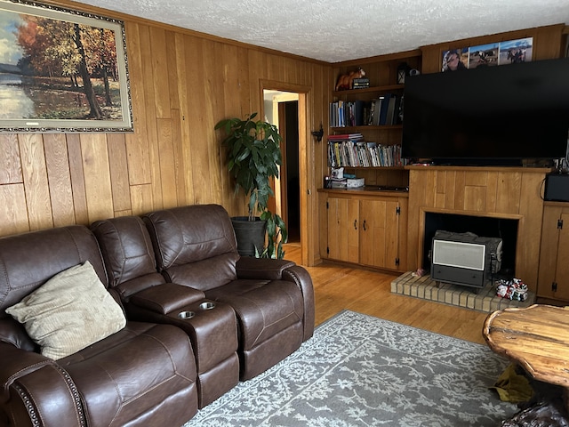 living room featuring a wood stove, wooden walls, light hardwood / wood-style floors, and a textured ceiling