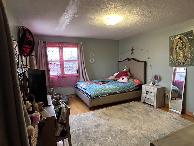 bedroom with light hardwood / wood-style flooring and a textured ceiling