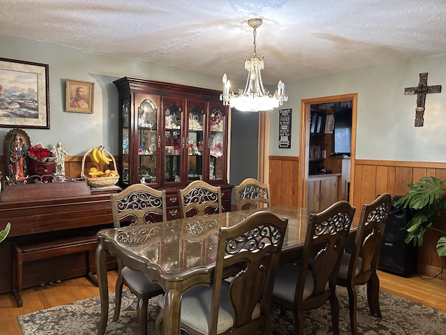 dining room featuring light hardwood / wood-style floors, a textured ceiling, and a notable chandelier