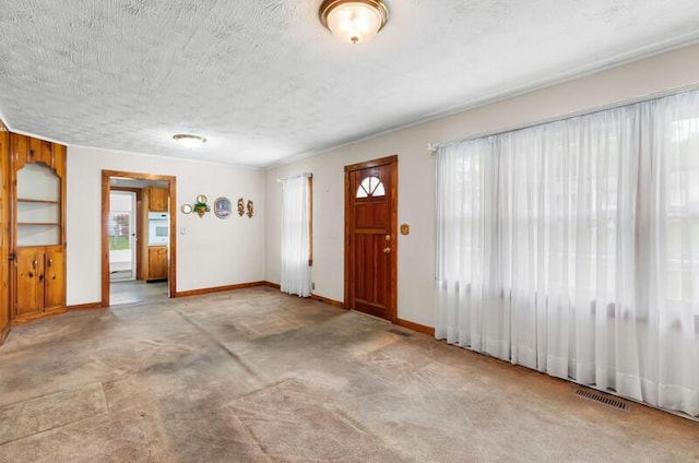 foyer featuring a textured ceiling, visible vents, and baseboards