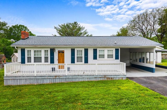 view of front of home with a carport, a chimney, a front yard, and aphalt driveway