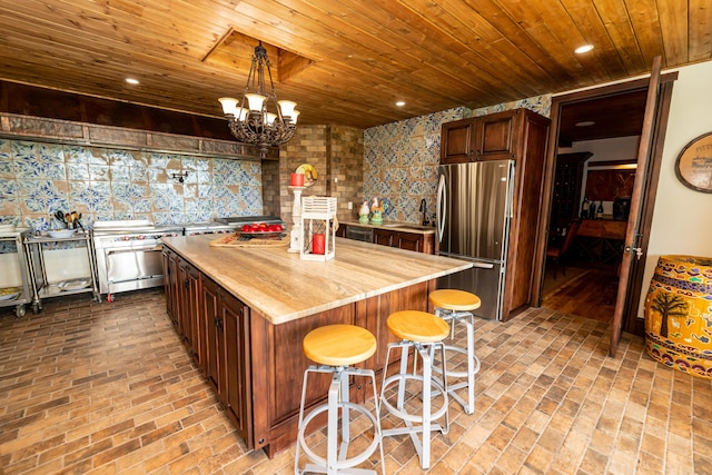 kitchen with stainless steel fridge, a kitchen breakfast bar, a notable chandelier, a center island, and hanging light fixtures