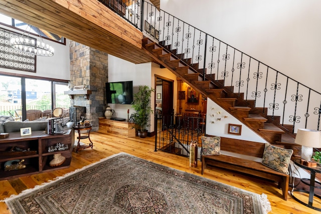 living room with a fireplace, a towering ceiling, wood-type flooring, and a notable chandelier