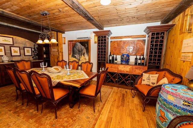 dining space with wooden ceiling, wooden walls, light wood-type flooring, a wall mounted AC, and beamed ceiling