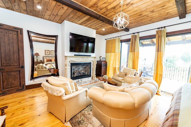 living room featuring a premium fireplace, beamed ceiling, a notable chandelier, light hardwood / wood-style floors, and wood ceiling