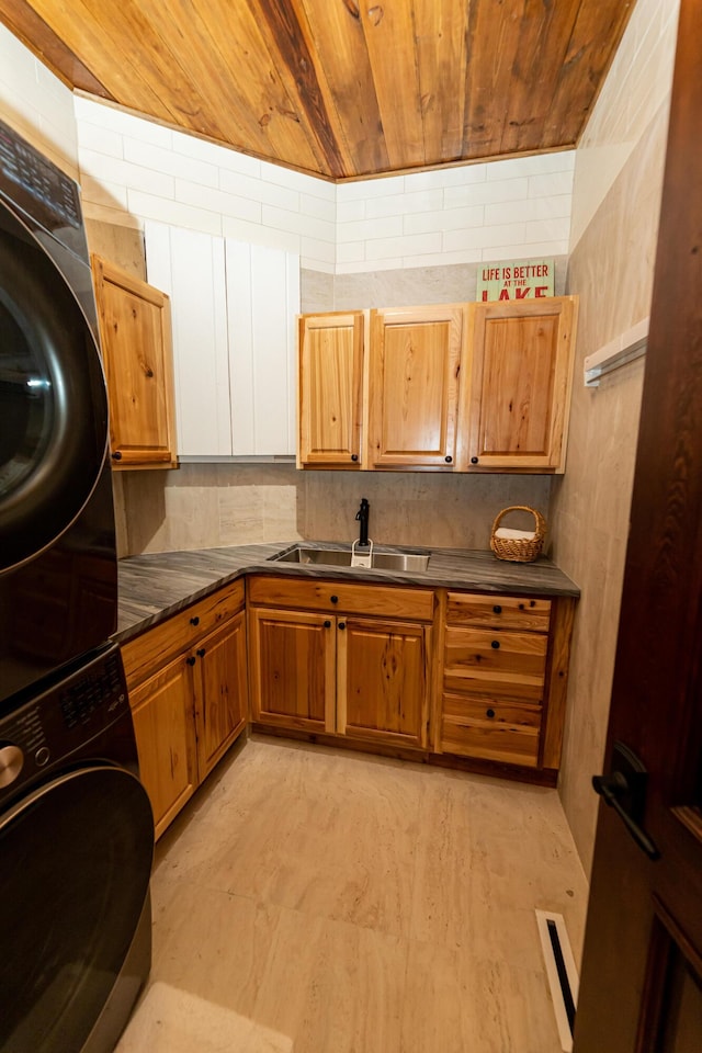 kitchen with wood ceiling, sink, and stacked washing maching and dryer