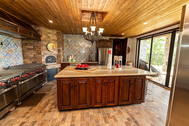 kitchen featuring a center island, an inviting chandelier, light stone counters, decorative light fixtures, and appliances with stainless steel finishes